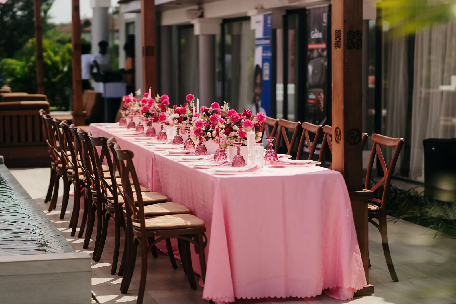 Rows of wooden chairs along a long table set with pink tablecloths and pink flower arrangements