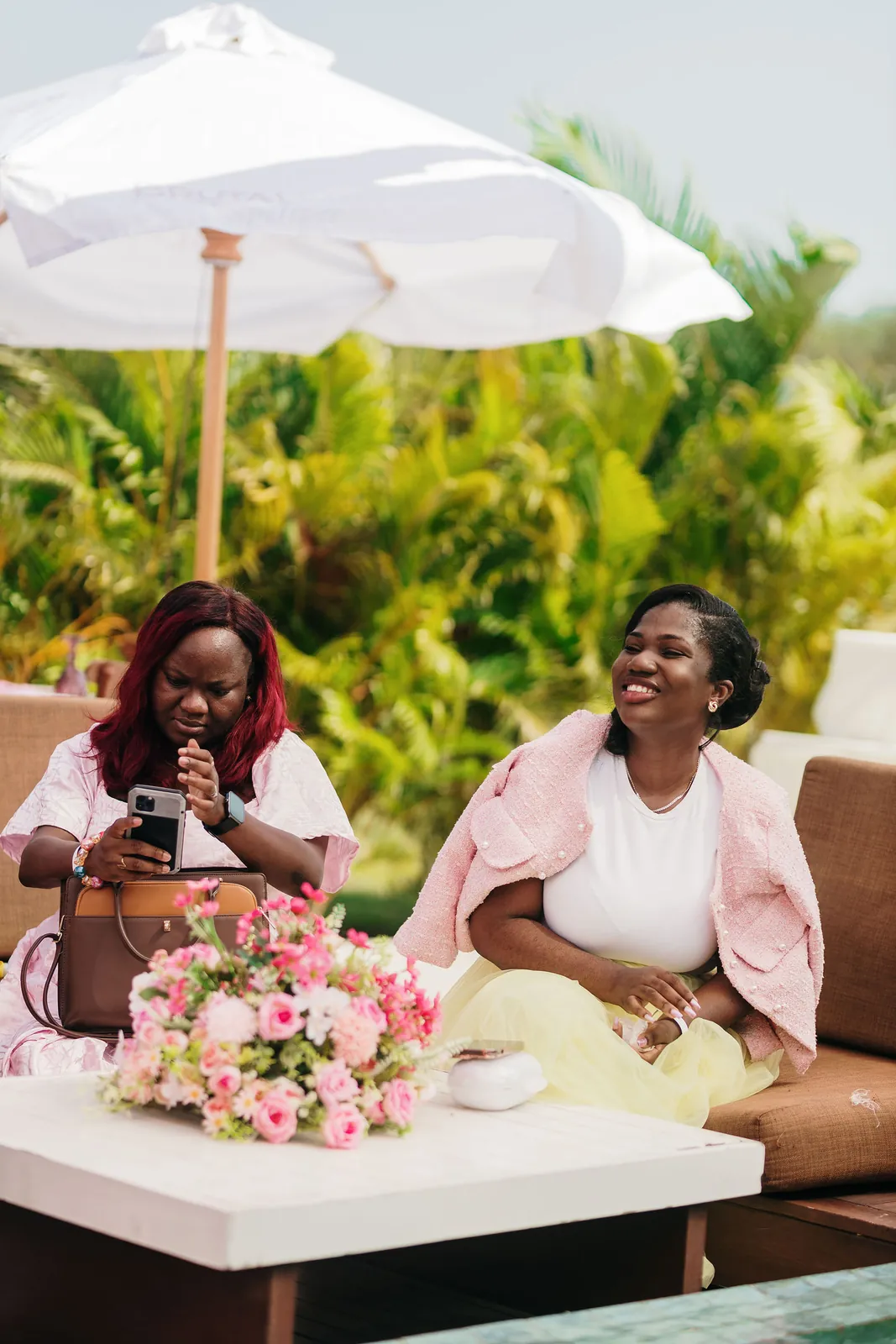 Two guests laughing together on a lounge sofa by the poolside