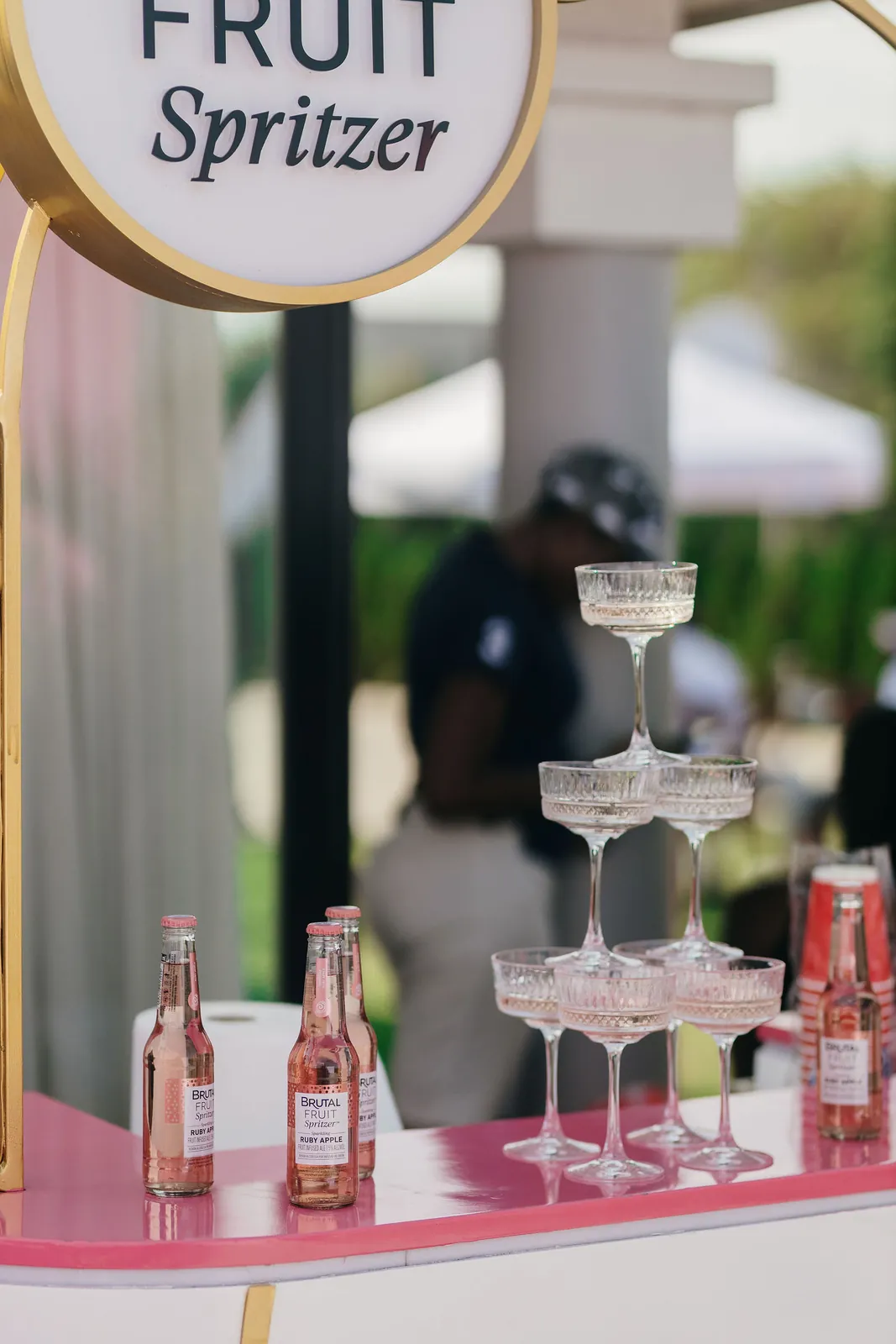 A champagne glass tower beside Brutal Fruit Spritzer bottles at the drinks bar