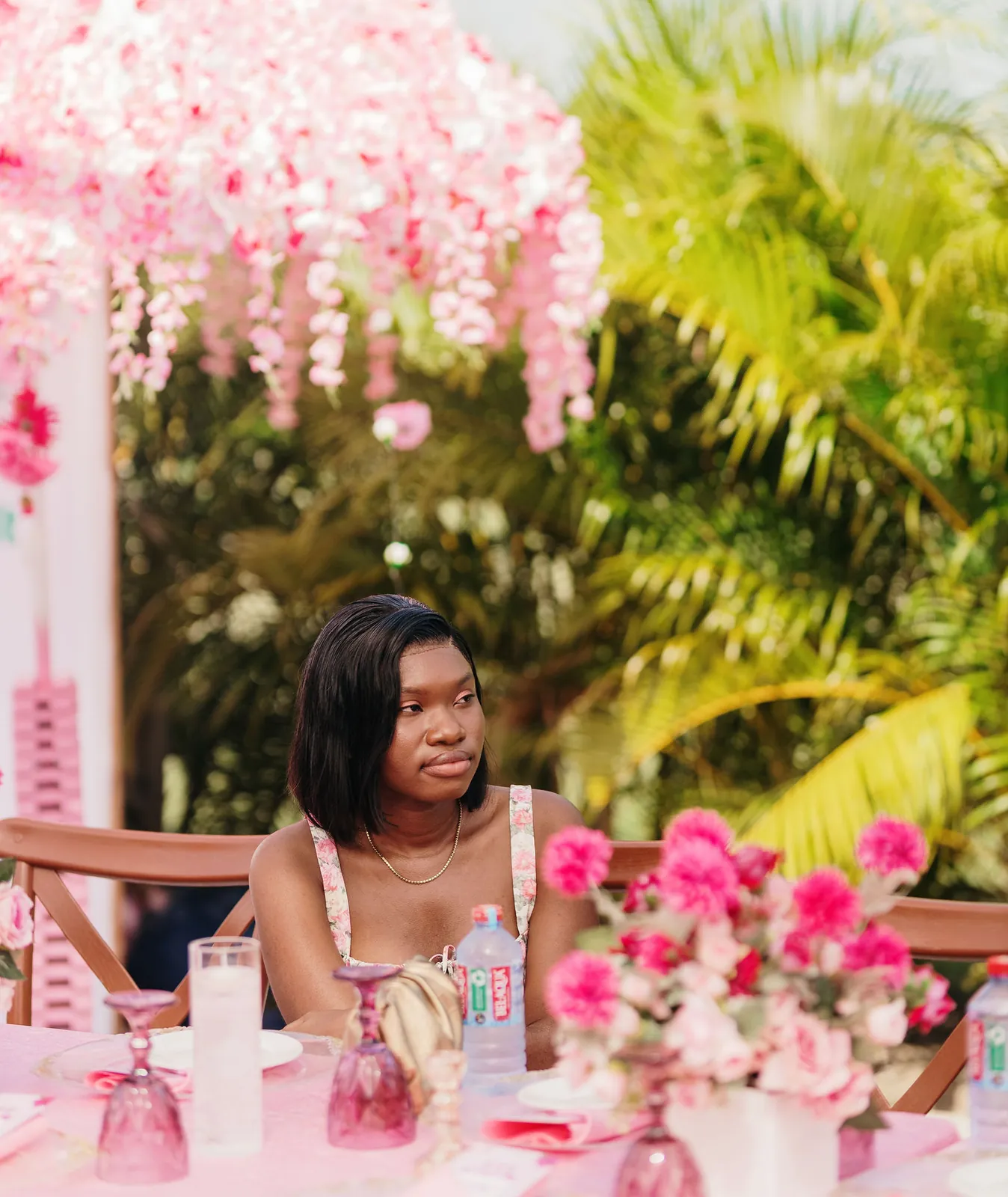 A guest seated at a flower-filled table under hanging pink blossoms