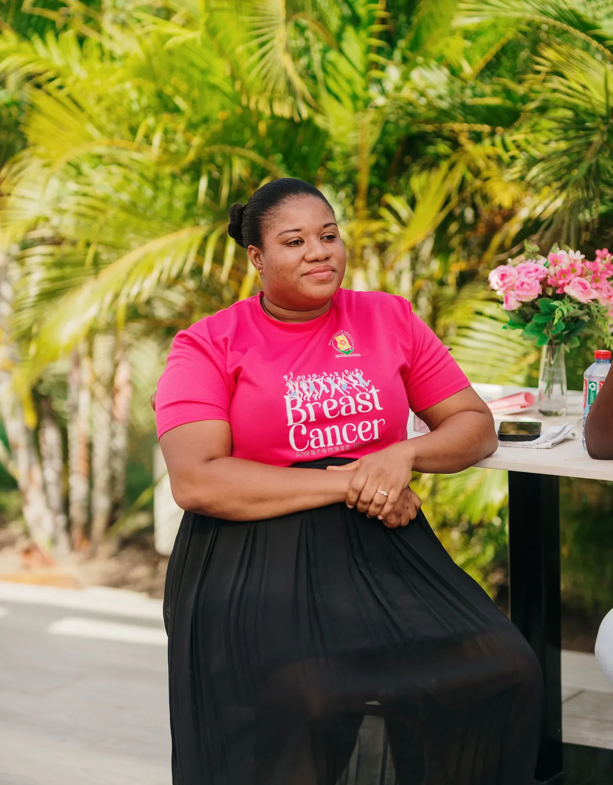 A speaker in a pink breast cancer awareness T-shirt addressing guests