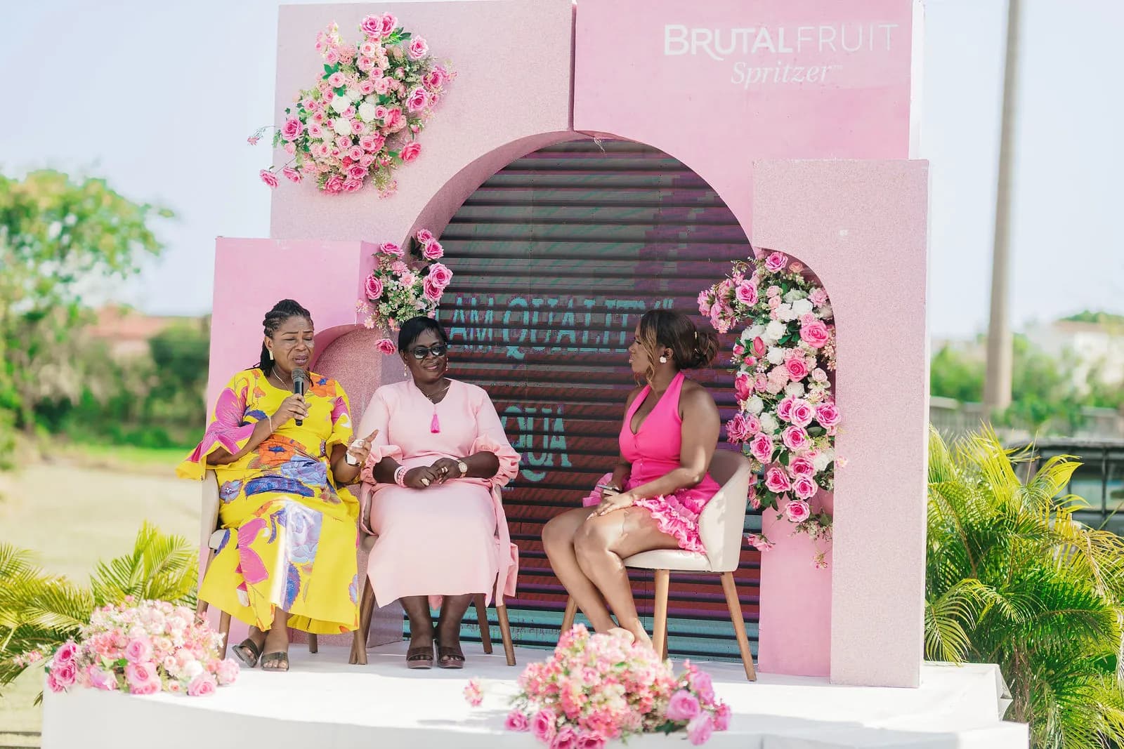 Three speakers in conversation on the pink stage during the panel session