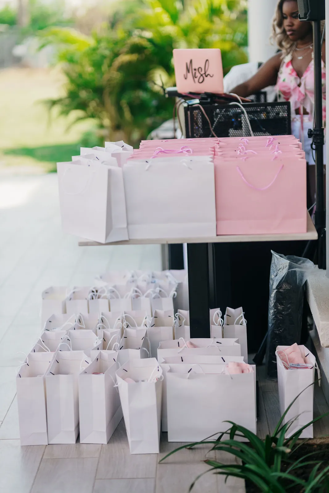 Pink and white gift bags arranged on a table for guests
