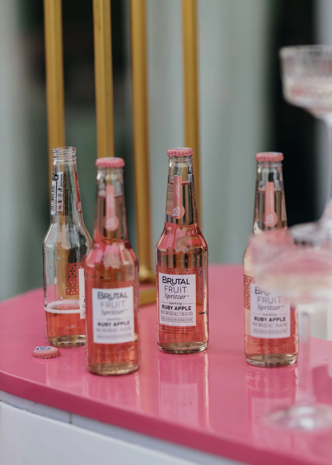Bottles of Brutal Fruit Spritzer lined up on a pink bar counter